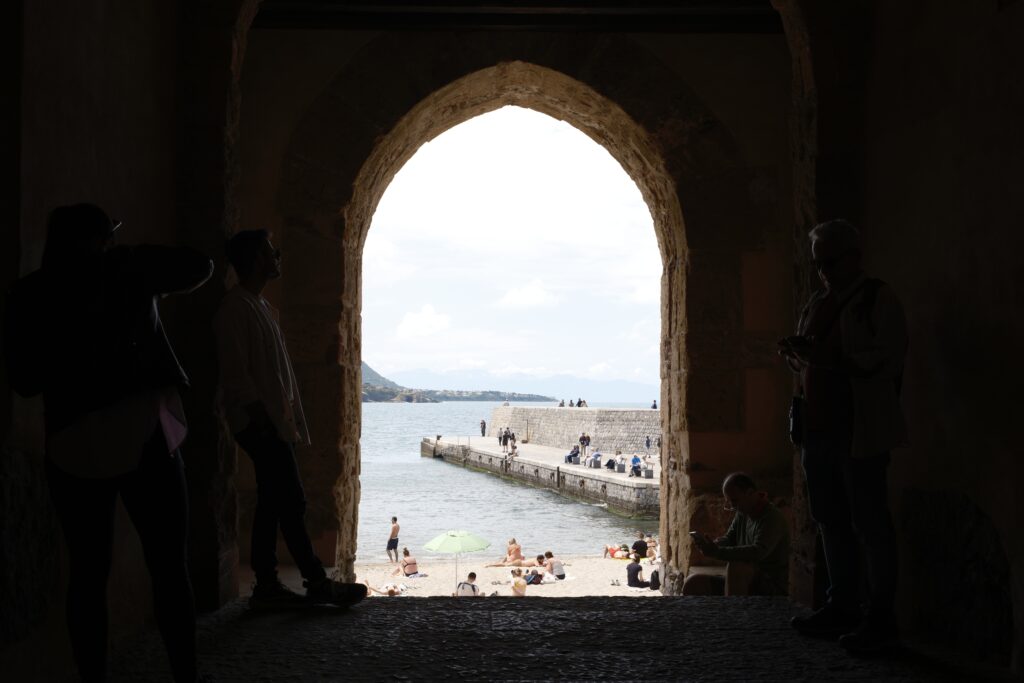 Blick durch ein mittelalterliches Steintor auf den Strand und die Mole von Cefalu